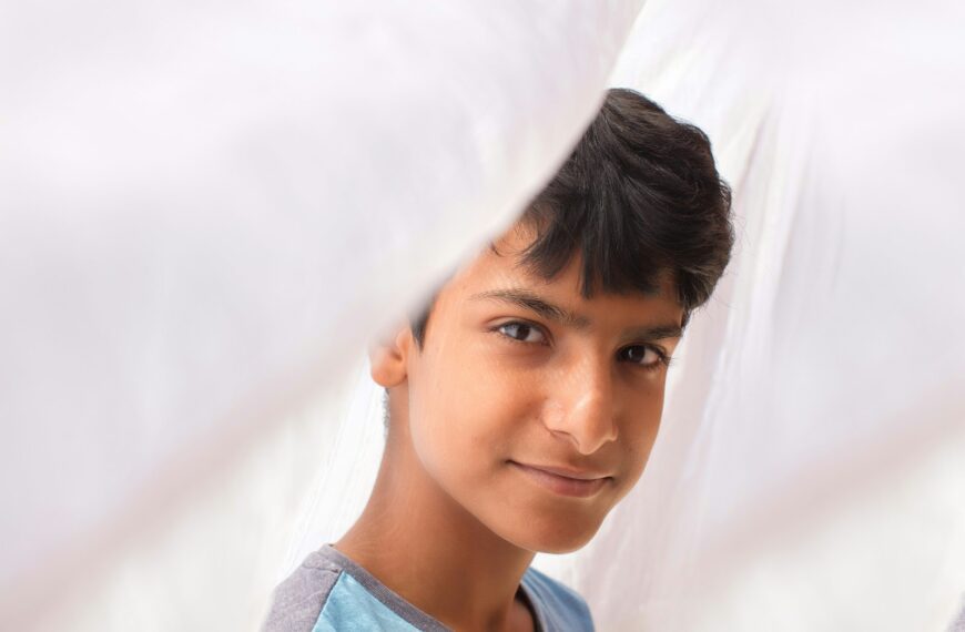 a young boy looking through a hole in a sheet