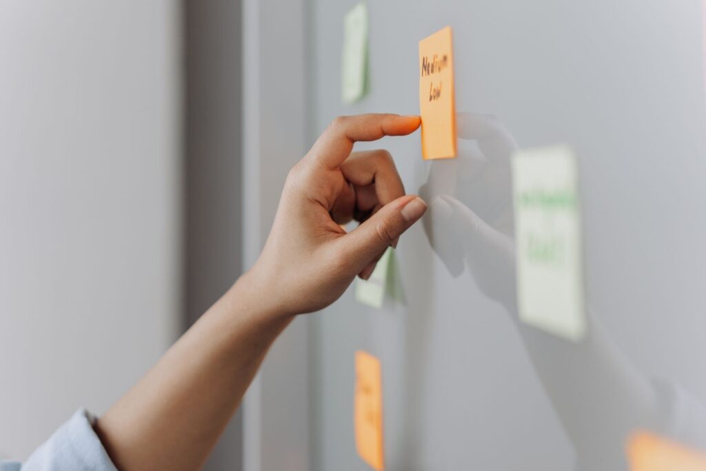 A hand placing a sticky note on a reflective surface in an office setting.
