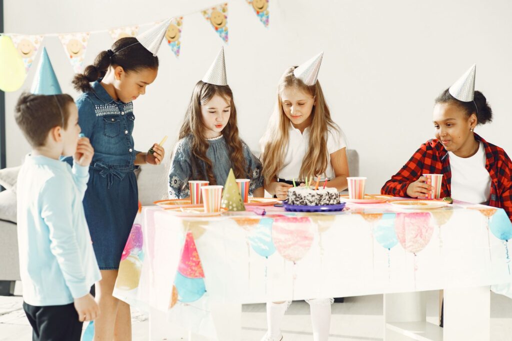A group of children enjoying a birthday party with cake and decorations indoors.