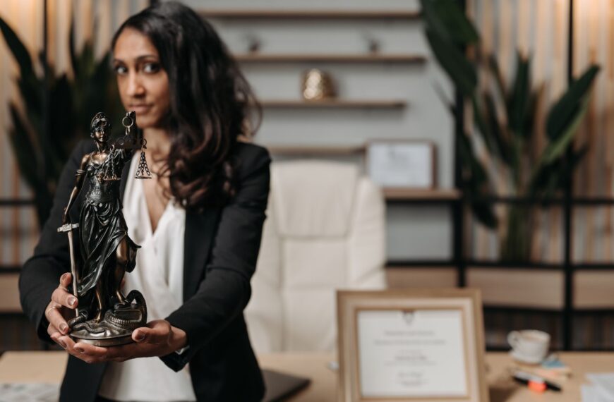 A female lawyer presenting a Lady Justice statue in a modern office setting.