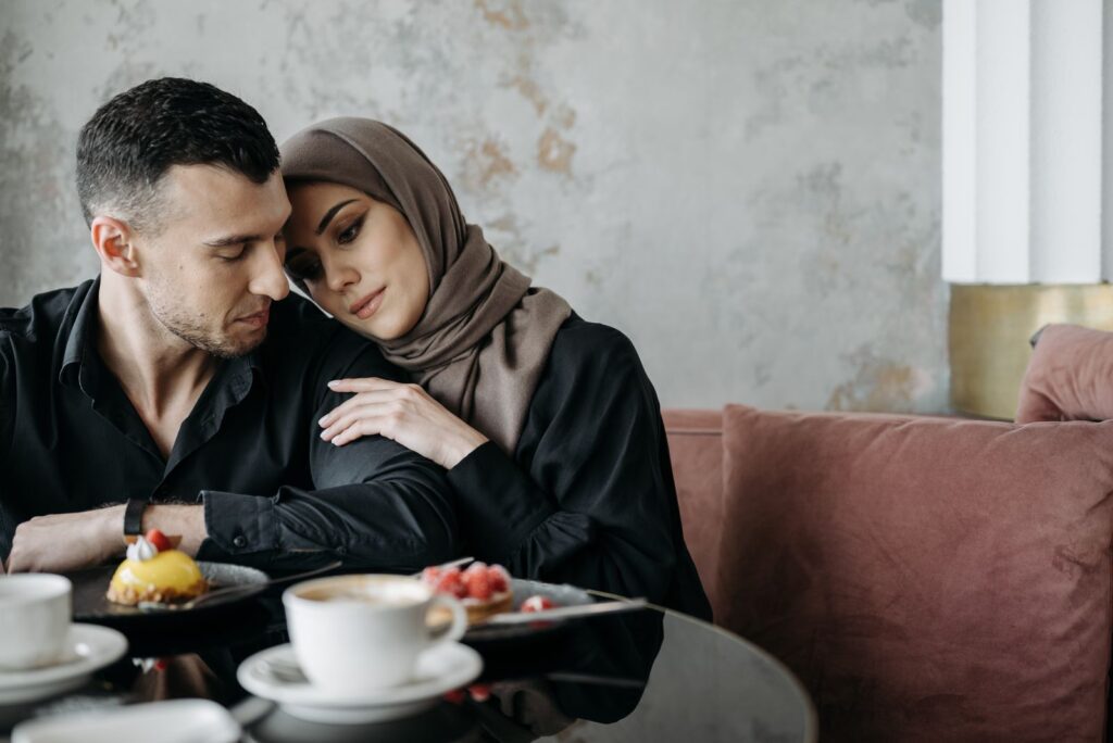 A loving Muslim couple sitting together in a cozy café setting, enjoying a serene moment.