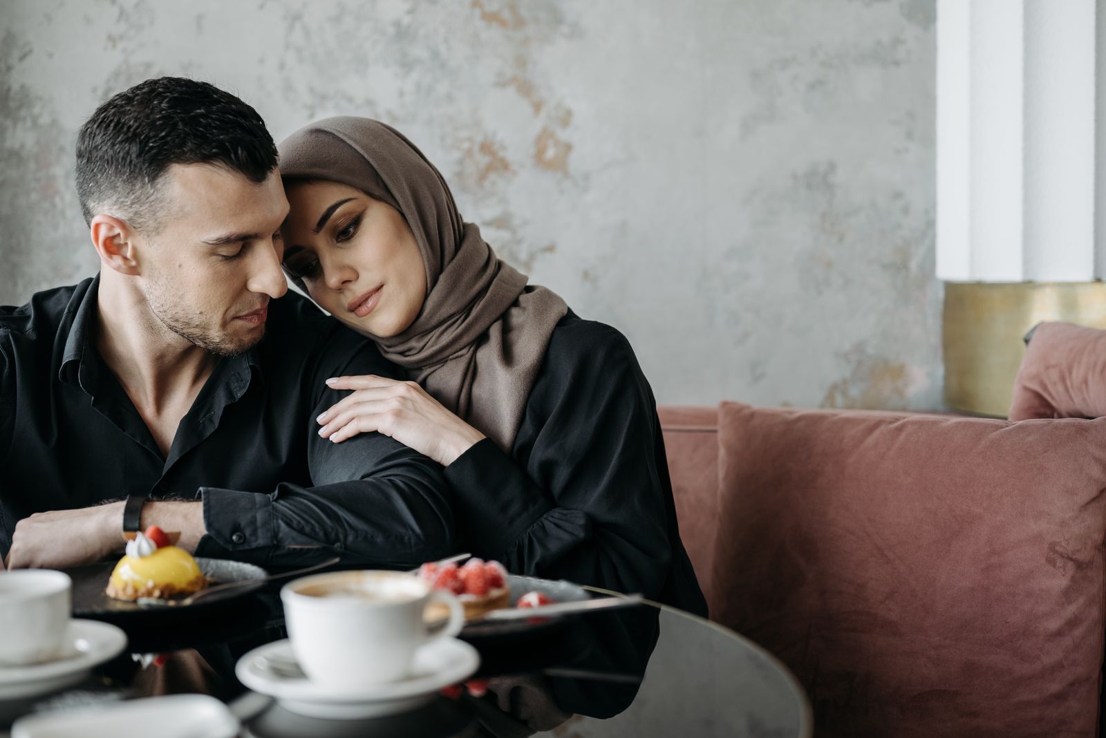 A loving Muslim couple sitting together in a cozy café setting, enjoying a serene moment.