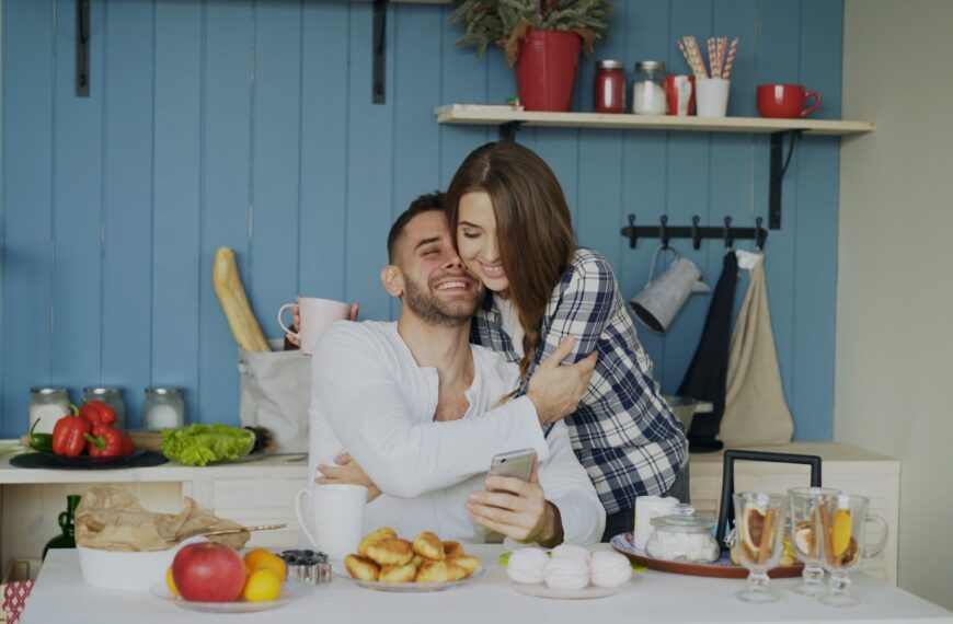 Couple hugging and smiling in a kitchen.