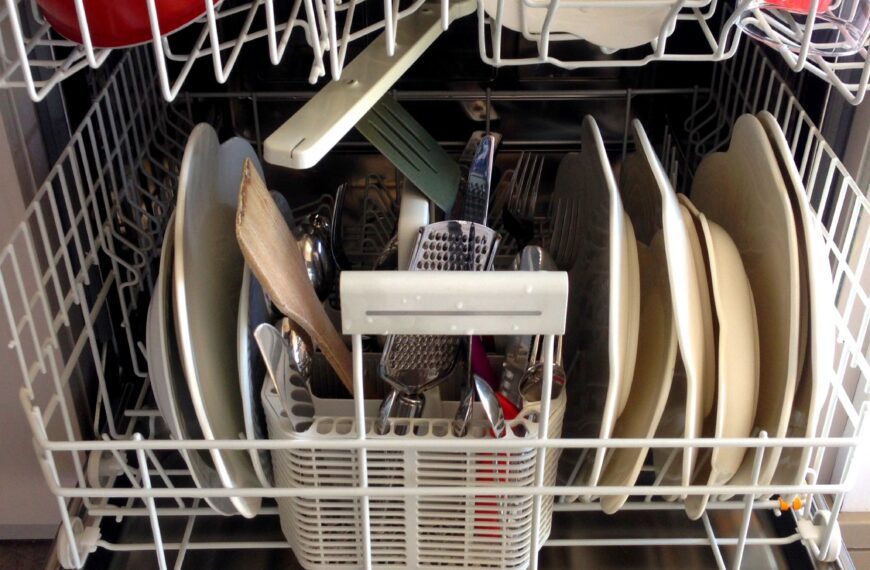 Modern dishwasher open and loaded with clean plates, bowls, and glassware