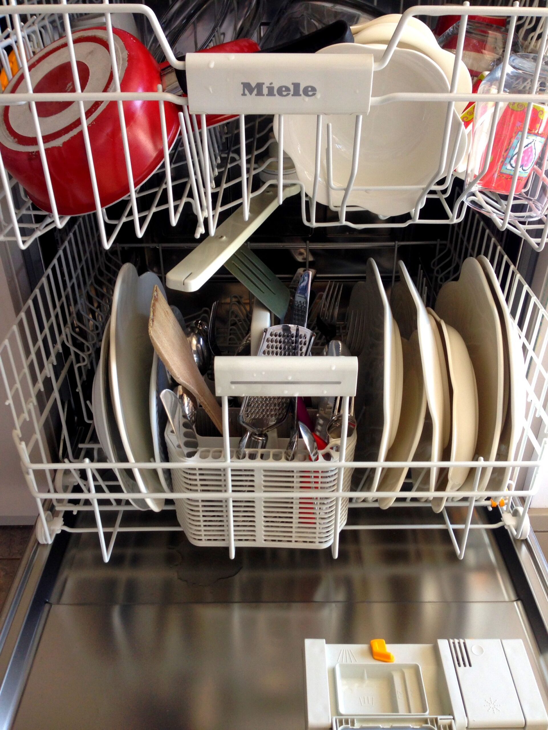Modern dishwasher open and loaded with clean plates, bowls, and glassware