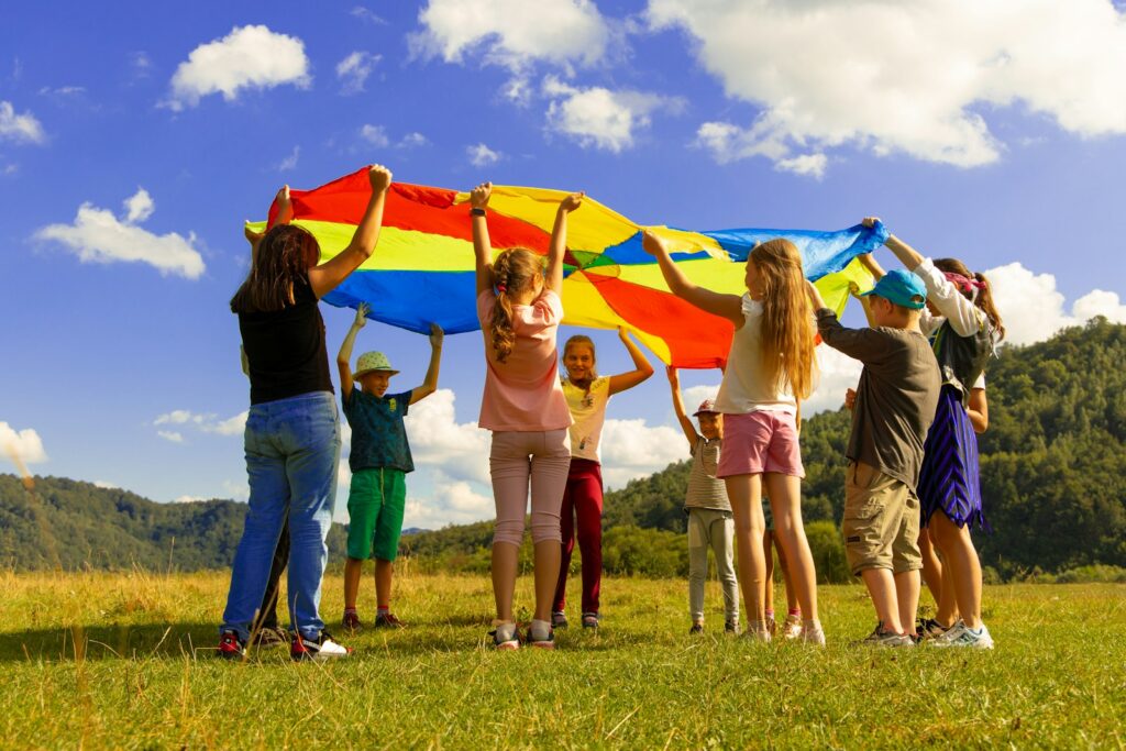 children playing with colorful parachute on grass