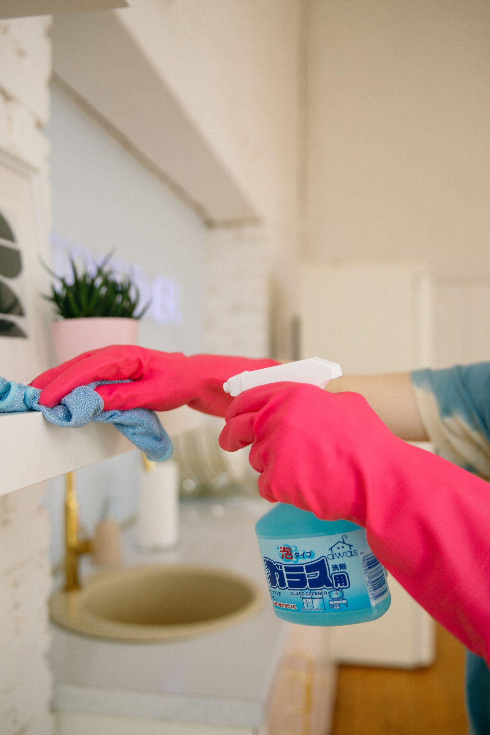 Person spraying a natural cleaning solution on a bright kitchen shelf while wiping with a cloth