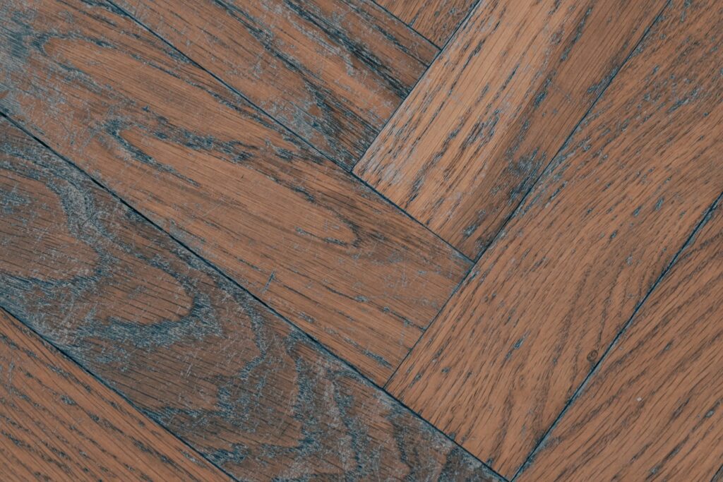 Close-up of a reddish-brown herringbone patterned hardwood floor showing warm wood grain