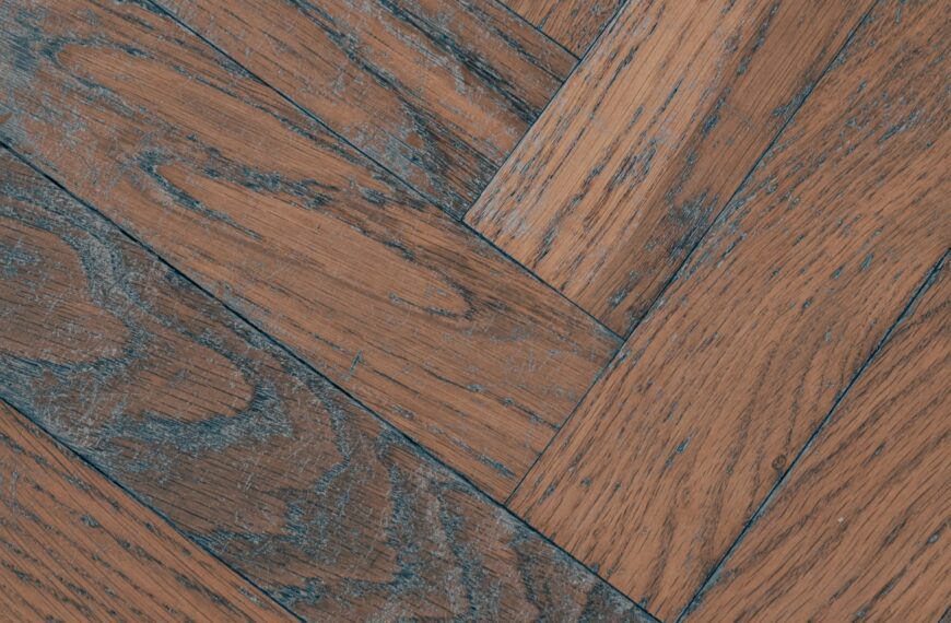 Close-up of a reddish-brown herringbone patterned hardwood floor showing warm wood grain