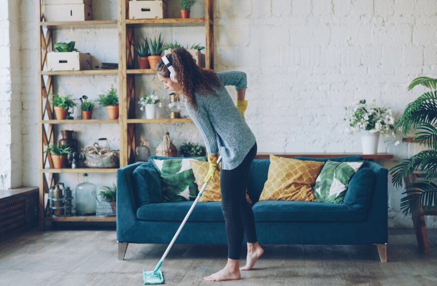 Woman mopping floor while wearing headphones.