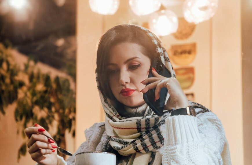 a woman talking on a cell phone while holding a cup of coffee