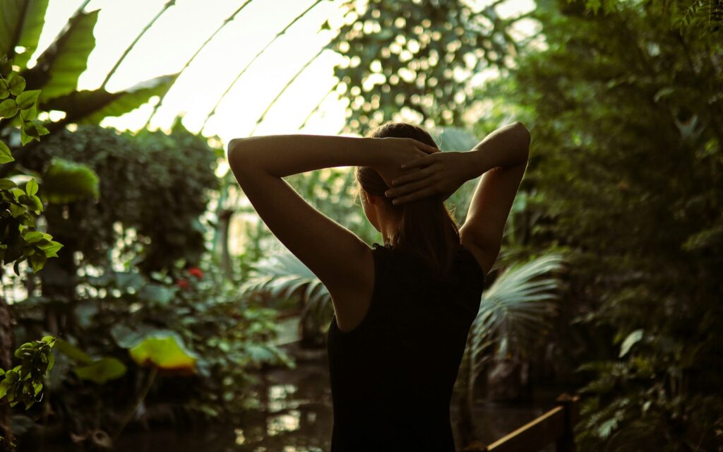 A woman in a black dress standing in a greenhouse
