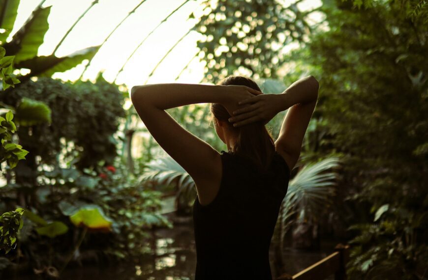 A woman in a black dress standing in a greenhouse
