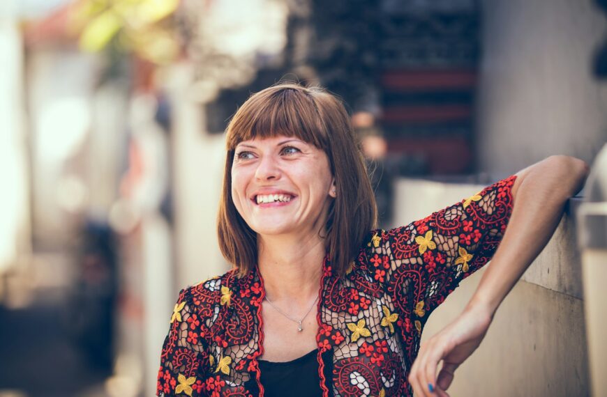 woman in floral-themed cardigan leaning on fence in bokeh photography