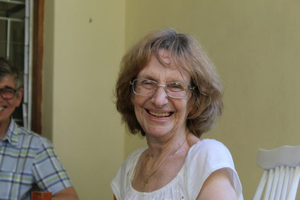 A smiling older woman with glasses and brown hair.