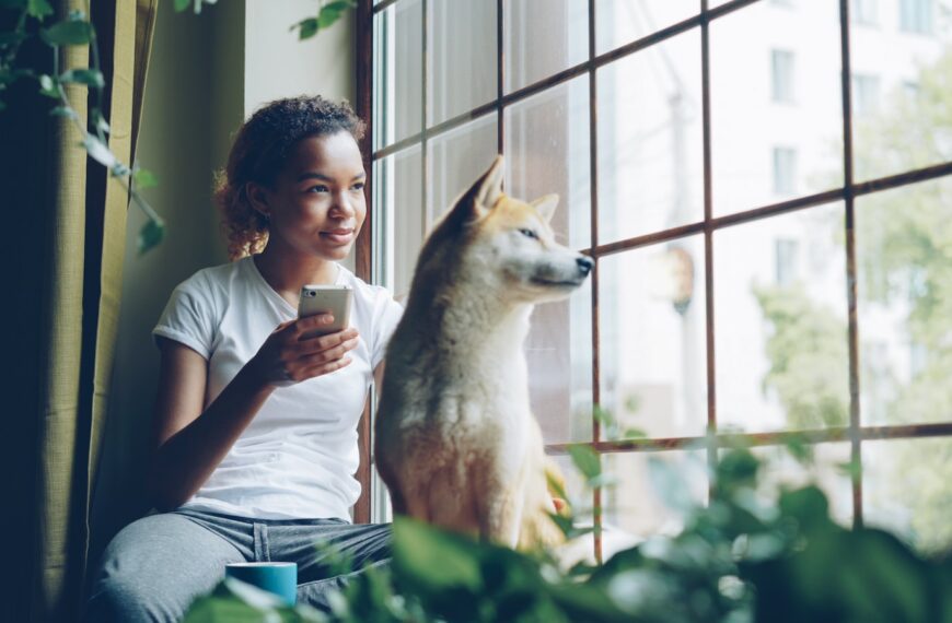 Woman and dog look out the window together.