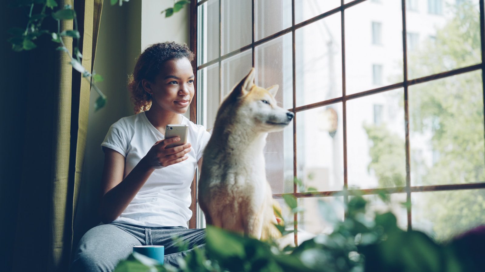 Woman and dog look out the window together.