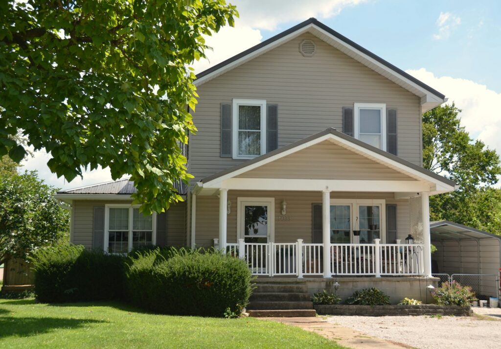 A two-story house with beige siding and a white front porch