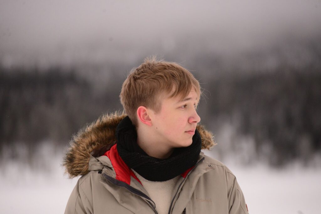 a young man standing in the snow wearing a jacket