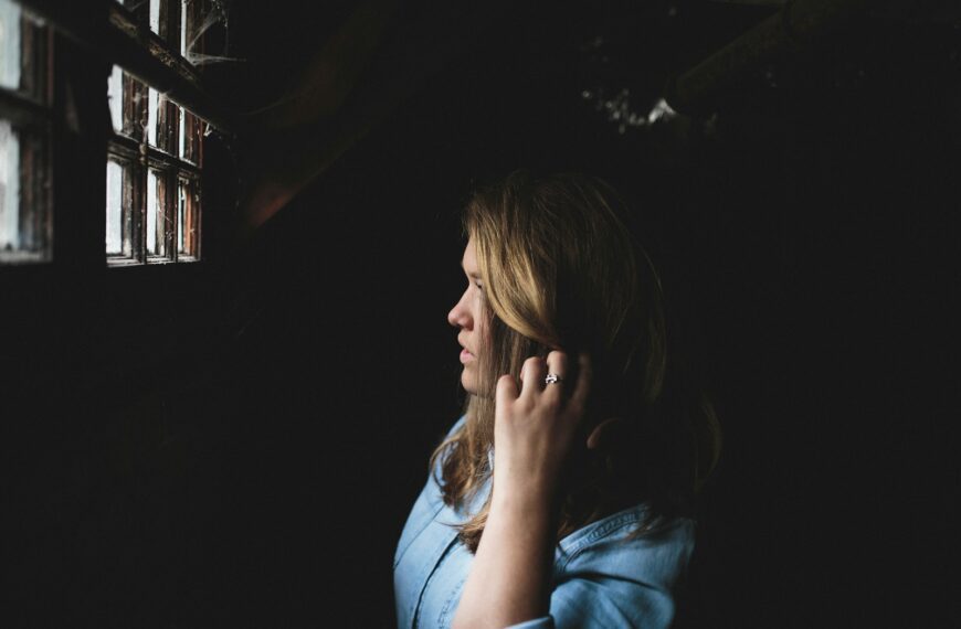woman touching her hair while looking at the window inside house
