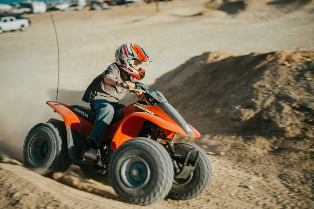 a man riding an orange four wheeler on a dirt road