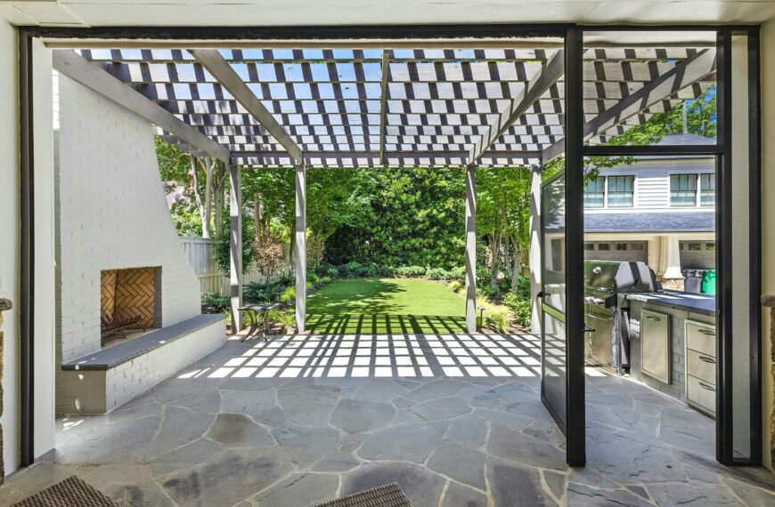 Modern backyard outdoor living space with a pergola, fireplace, and outdoor kitchen zone