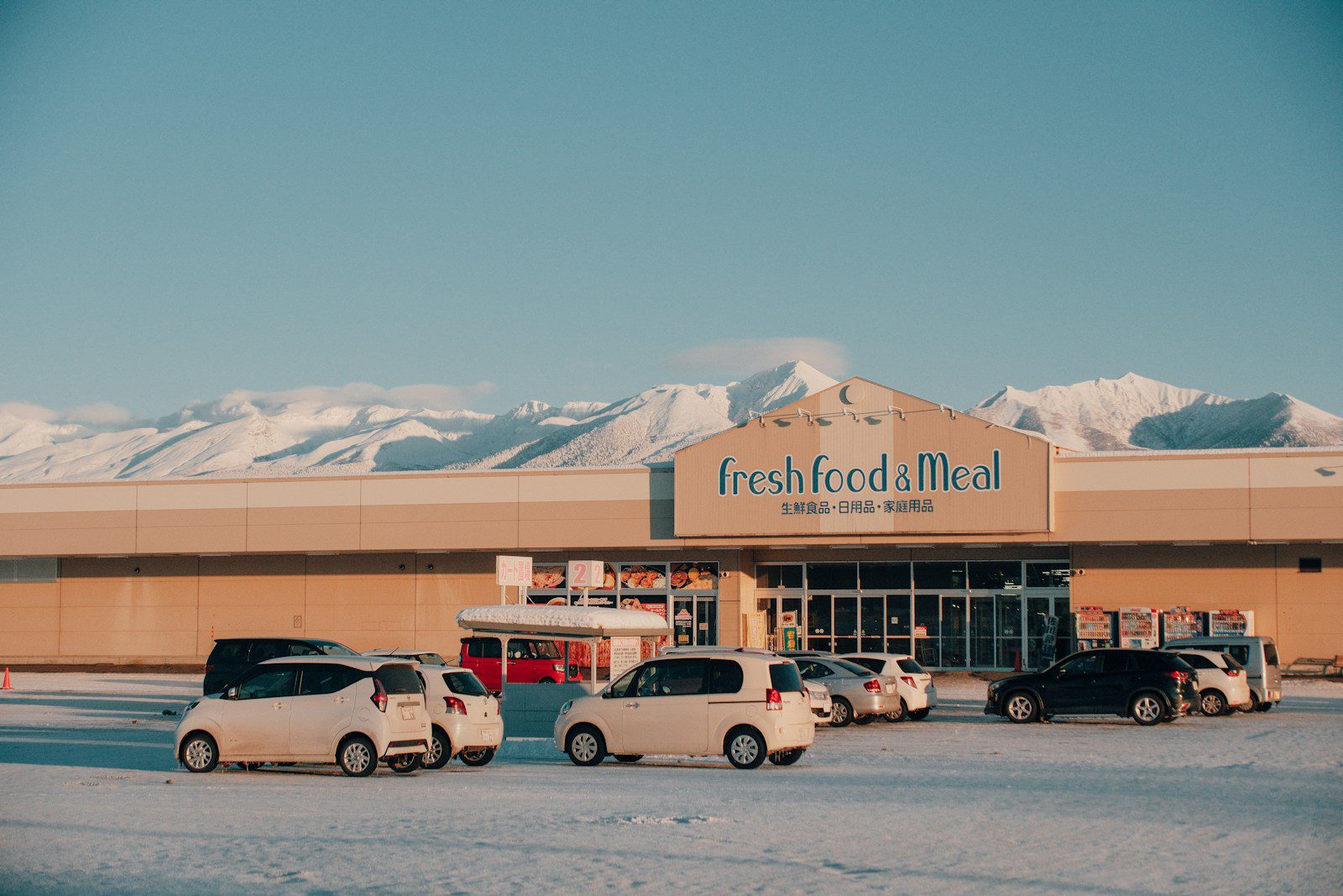 Cars parked in front of a store with mountains behind