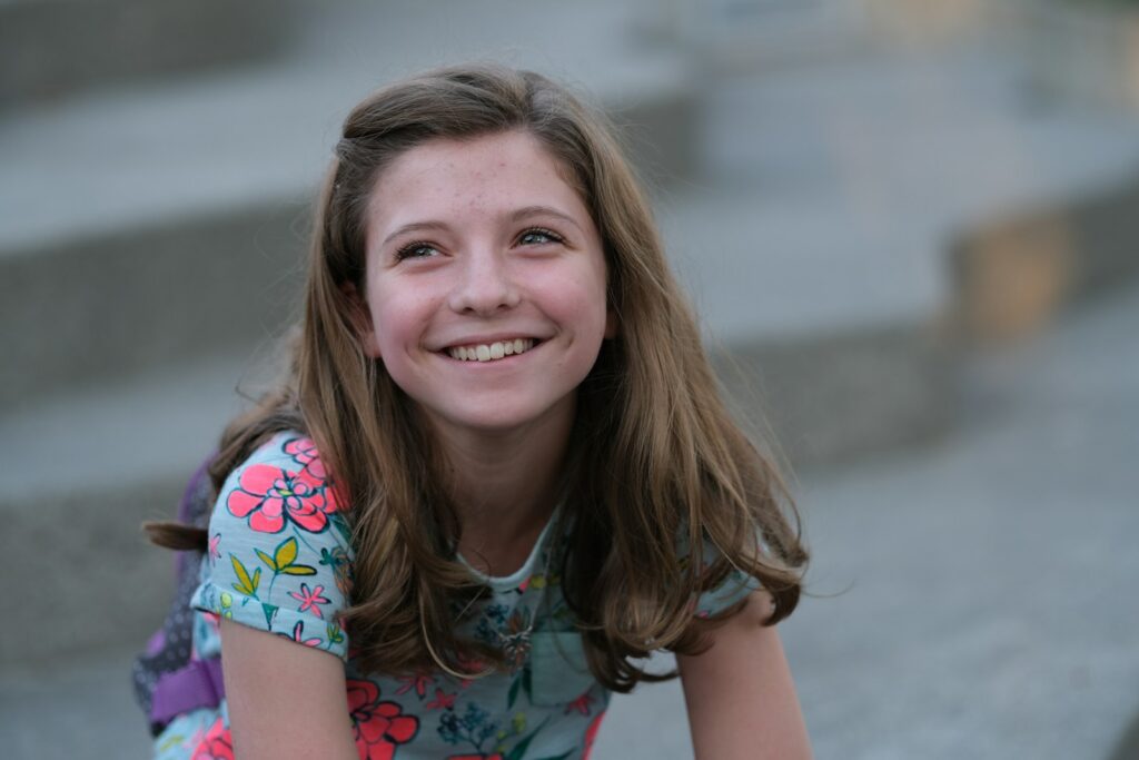A young girl sitting on steps smiling for the camera