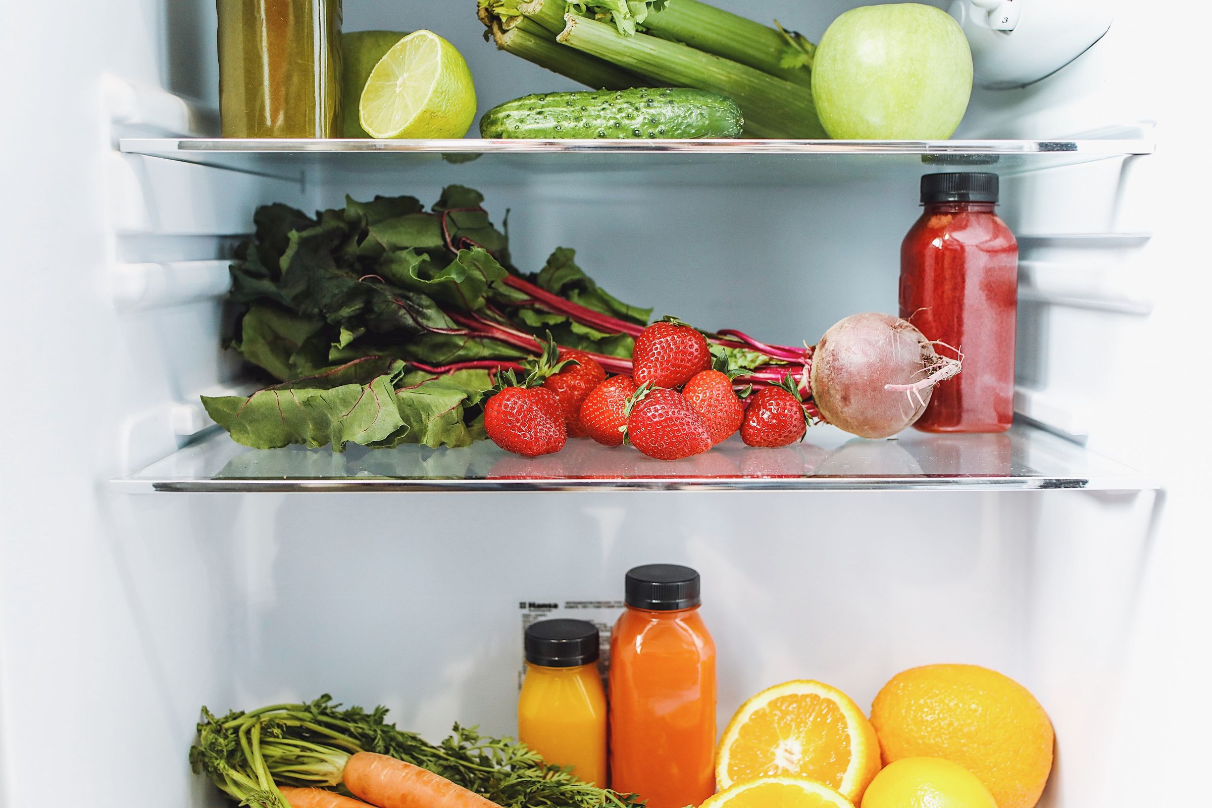 An organized refrigerator filled with colorful fresh fruits and vegetables