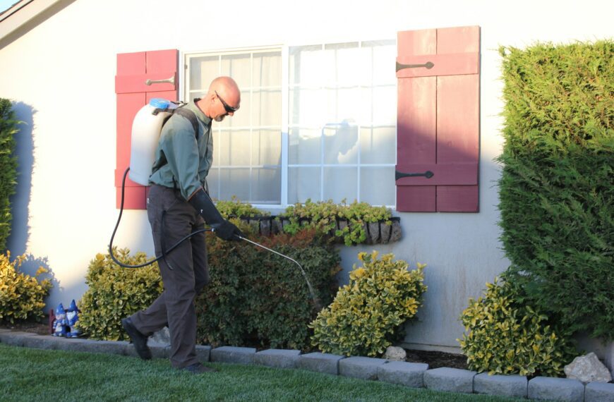 Pest control technician inspecting a home exterior for rodent entry points