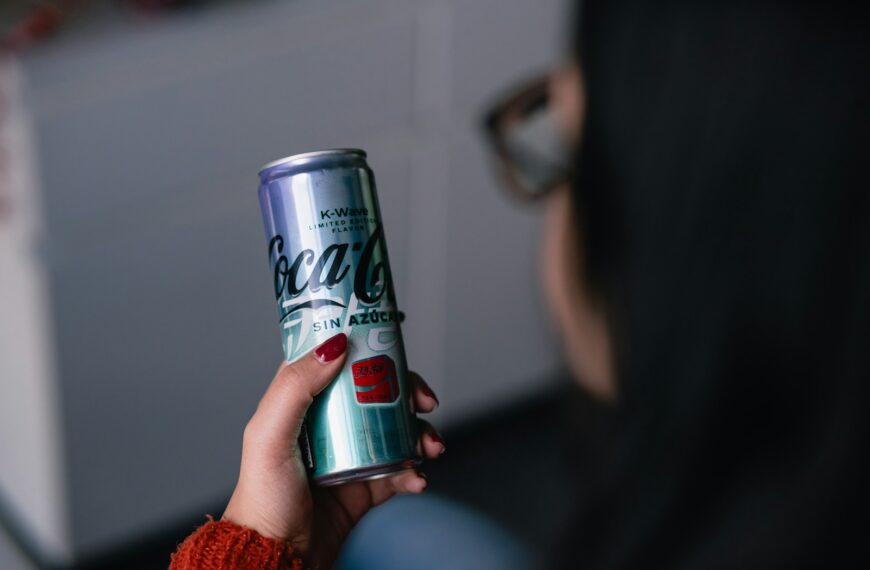 a woman holding a can of coca cola