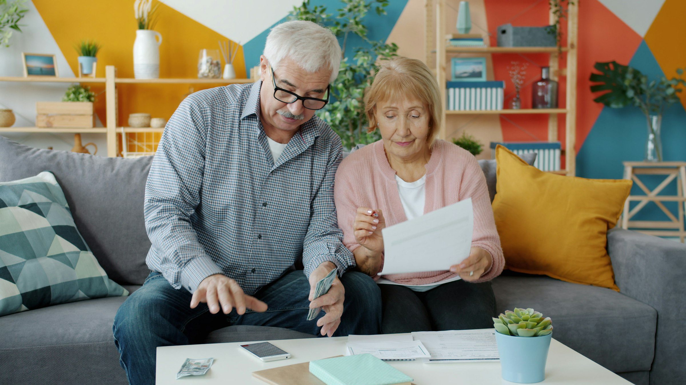 Couple sitting at a table reviewing financial paperwork and documents at home, calculating home equity and sale costs