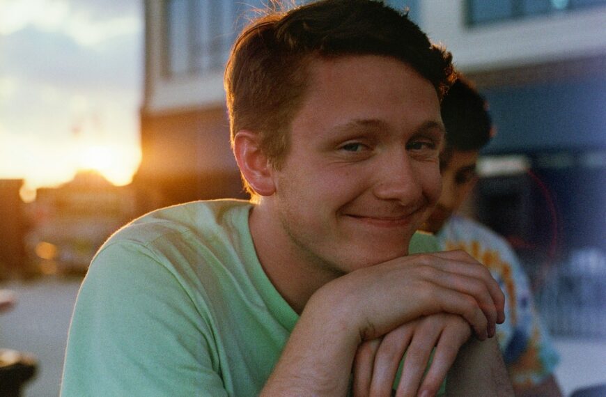 smiling man in green crew-neck shirt near building