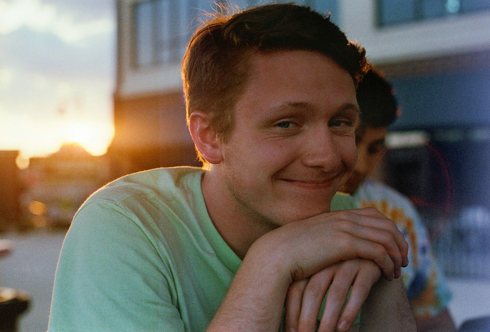 smiling man in green crew-neck shirt near building