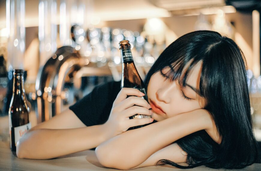 woman in black tank top holding brown glass bottle