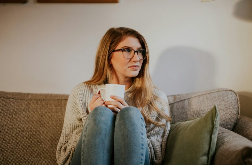 woman in blue denim jeans sitting on gray sofa