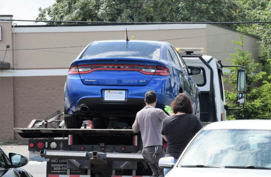 a blue car being loaded onto a flatbed truck