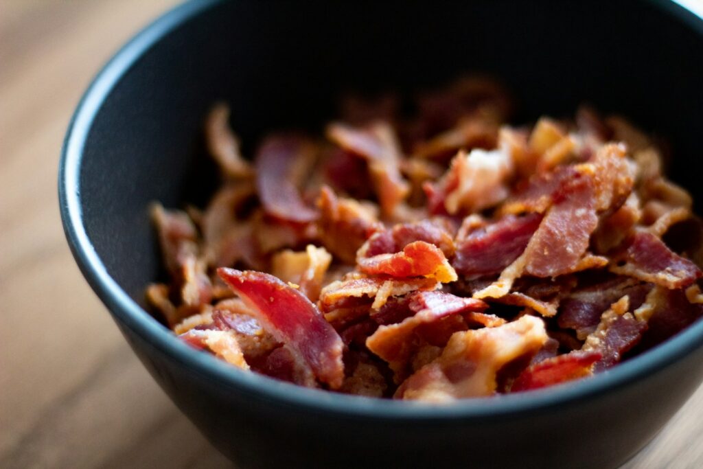 Crispy bacon pieces fill a black bowl.