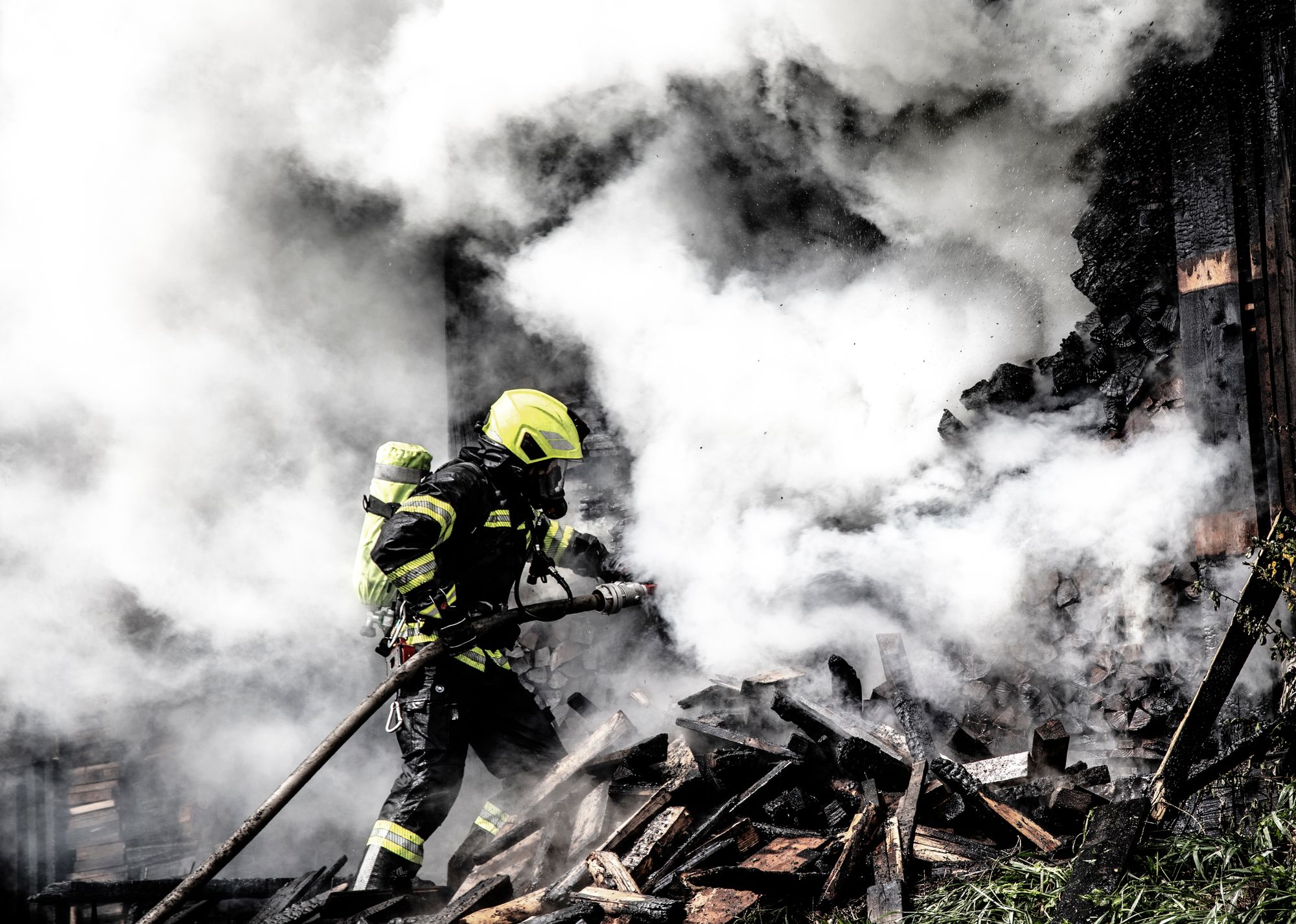 Firefighter working to contain raging wildfire flames and thick smoke, representing crews responding to fast-moving fires like the Hawk Fire
