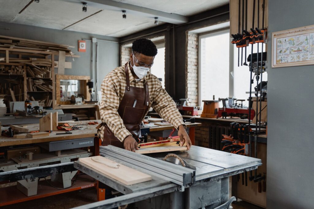 Professional woodworker wearing safety gear while using a saw in a well-lit home workshop