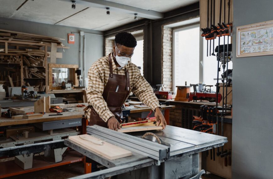 Professional woodworker wearing safety gear while using a saw in a well-lit home workshop