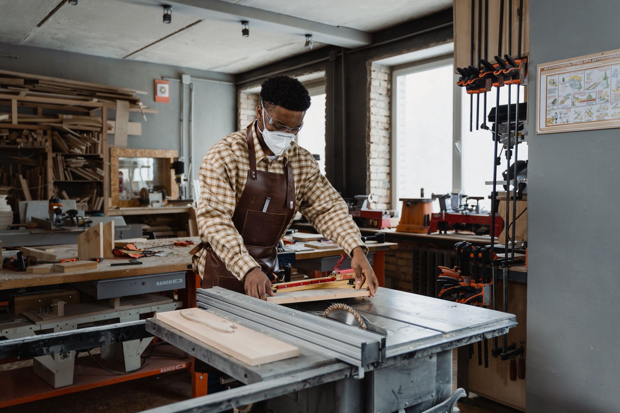 Professional woodworker wearing safety gear while using a saw in a well-lit home workshop