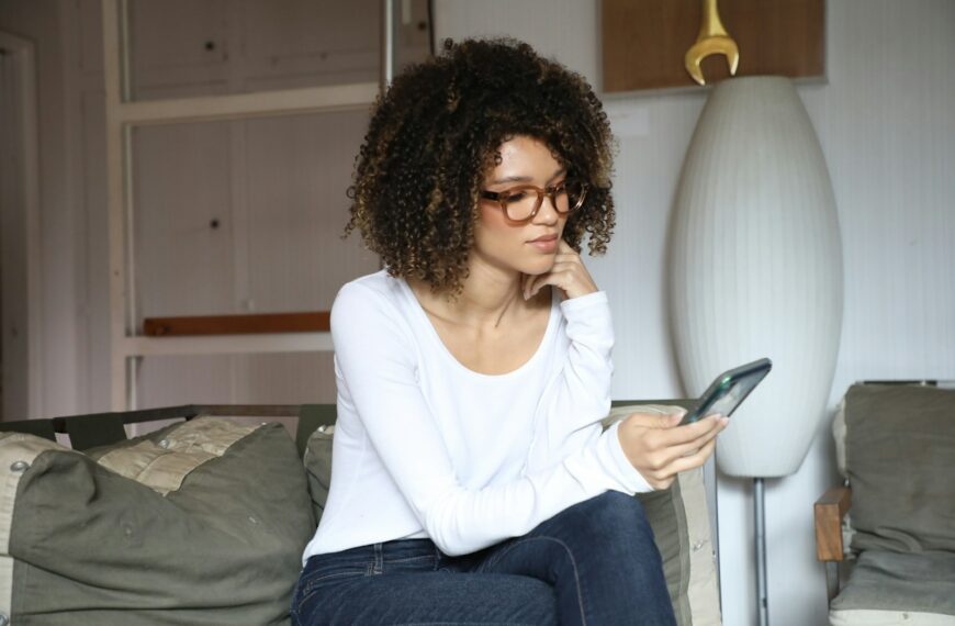 woman in white long sleeve shirt and blue denim jeans sitting on bed