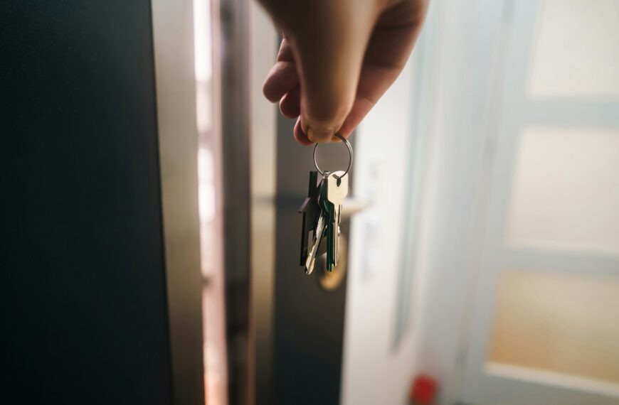 A hand holds a keyring near an open door.