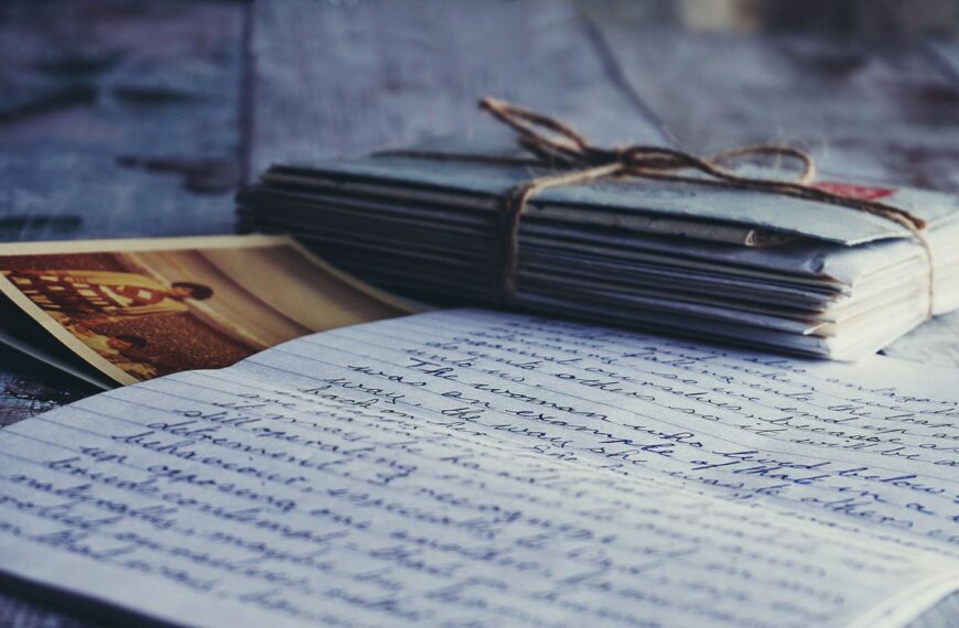 Stack of vintage letters and photographs tied with string on a rustic wooden table.