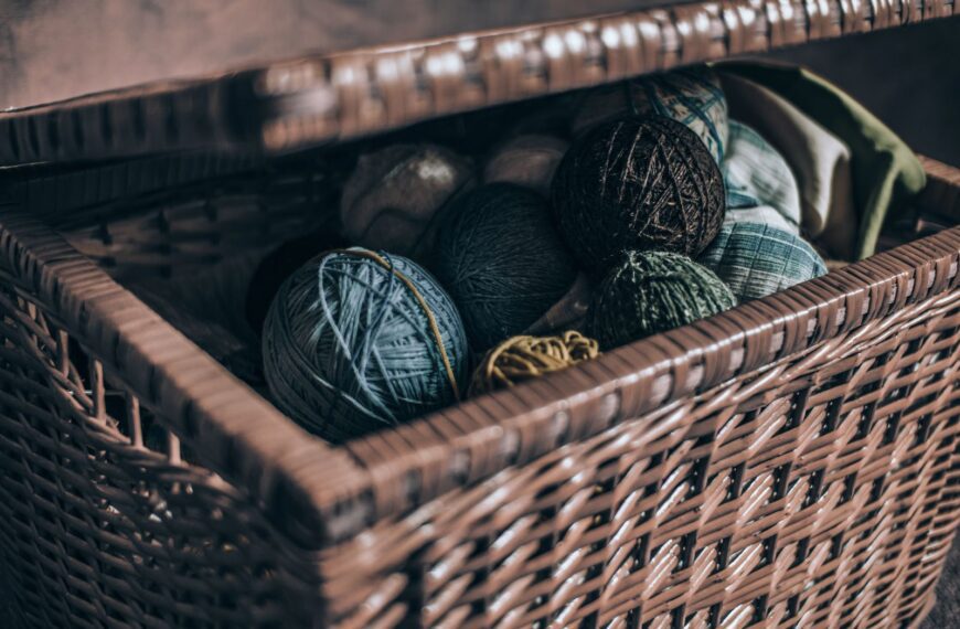 A close-up view of colorful yarn rolls inside an open woven basket.