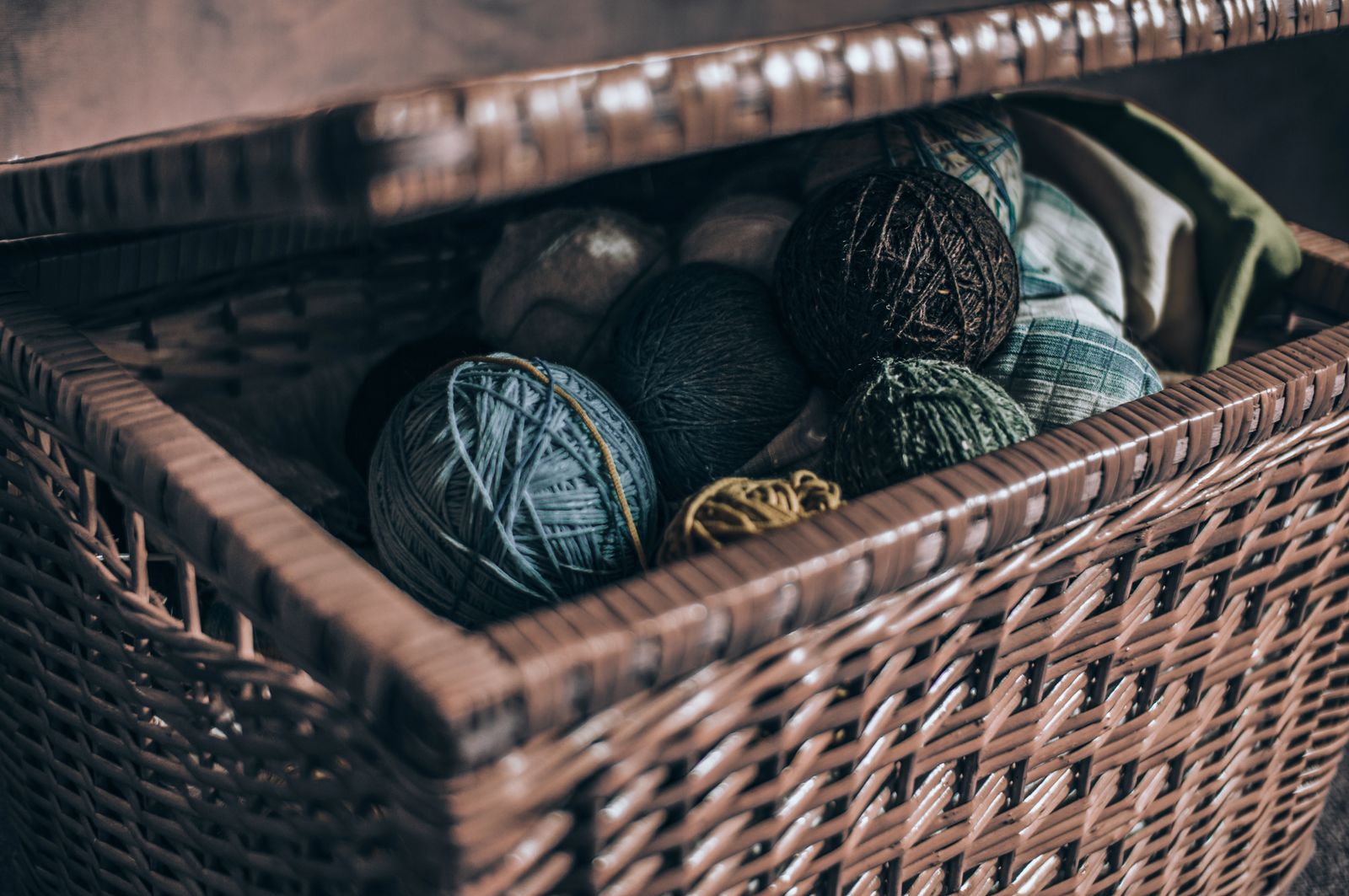 A close-up view of colorful yarn rolls inside an open woven basket.