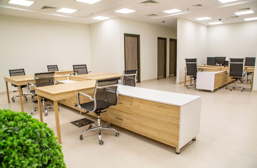 Spacious office interior with wooden desks and ergonomic chairs, perfect for a productive workday.