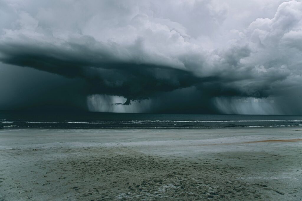 A powerful storm looms over a deserted beach, creating a dramatic skyscape.
