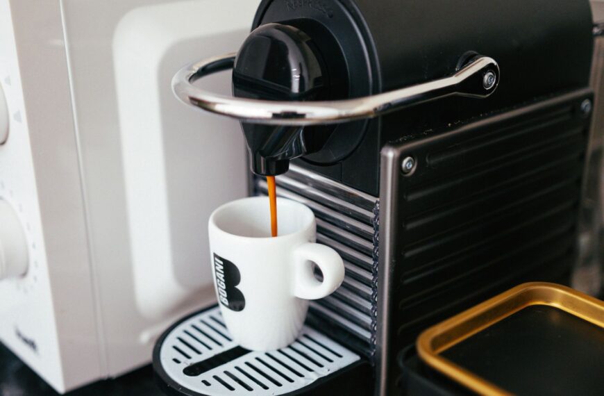 Close-up of a modern coffee machine brewing espresso into a branded mug indoors.